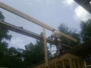 Carpenter setting a ridge beam over a new addition frame — Ice Dam Removal by Roofing Brothers in Waldron