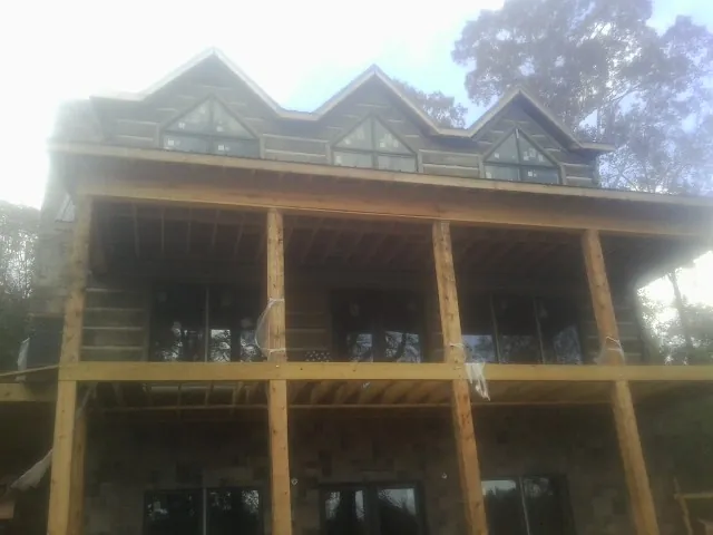 Dormers and porch framing on a large log home under construction — Roof Coating work by our crew in Waldron
