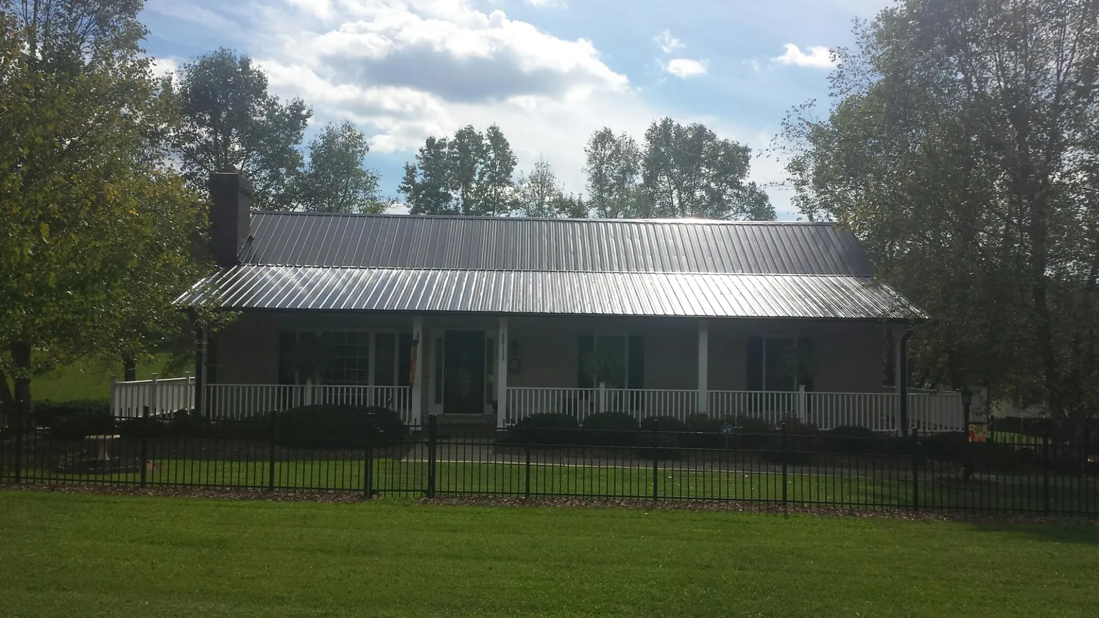 Gray metal roof on a brick ranch with a full width front porch — Gutter Guard Installation work by our crew in Waldron