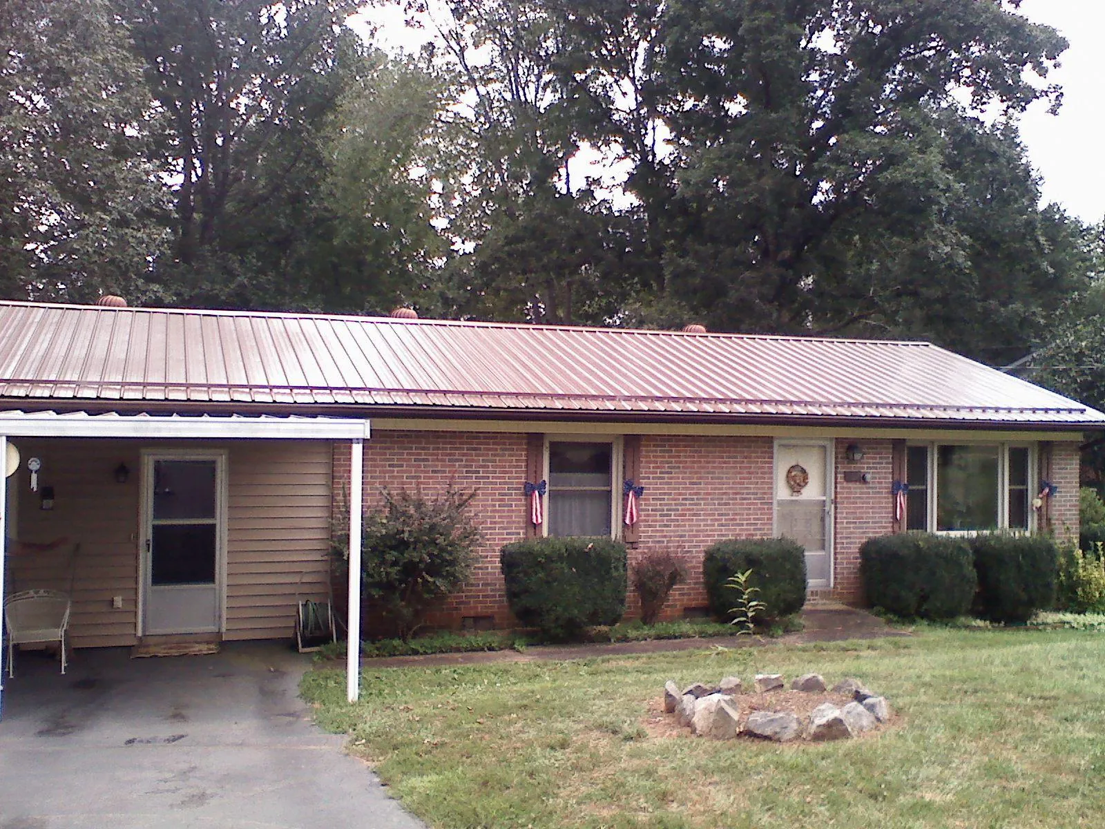 Bronze metal roof and carport on a brick ranch home — Roof Repair work by our crew in Waldron