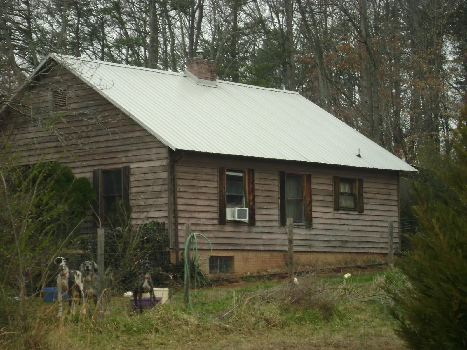 White metal roof on an old wood sided farmhouse, from a Metal Roof Installation job in Waldron