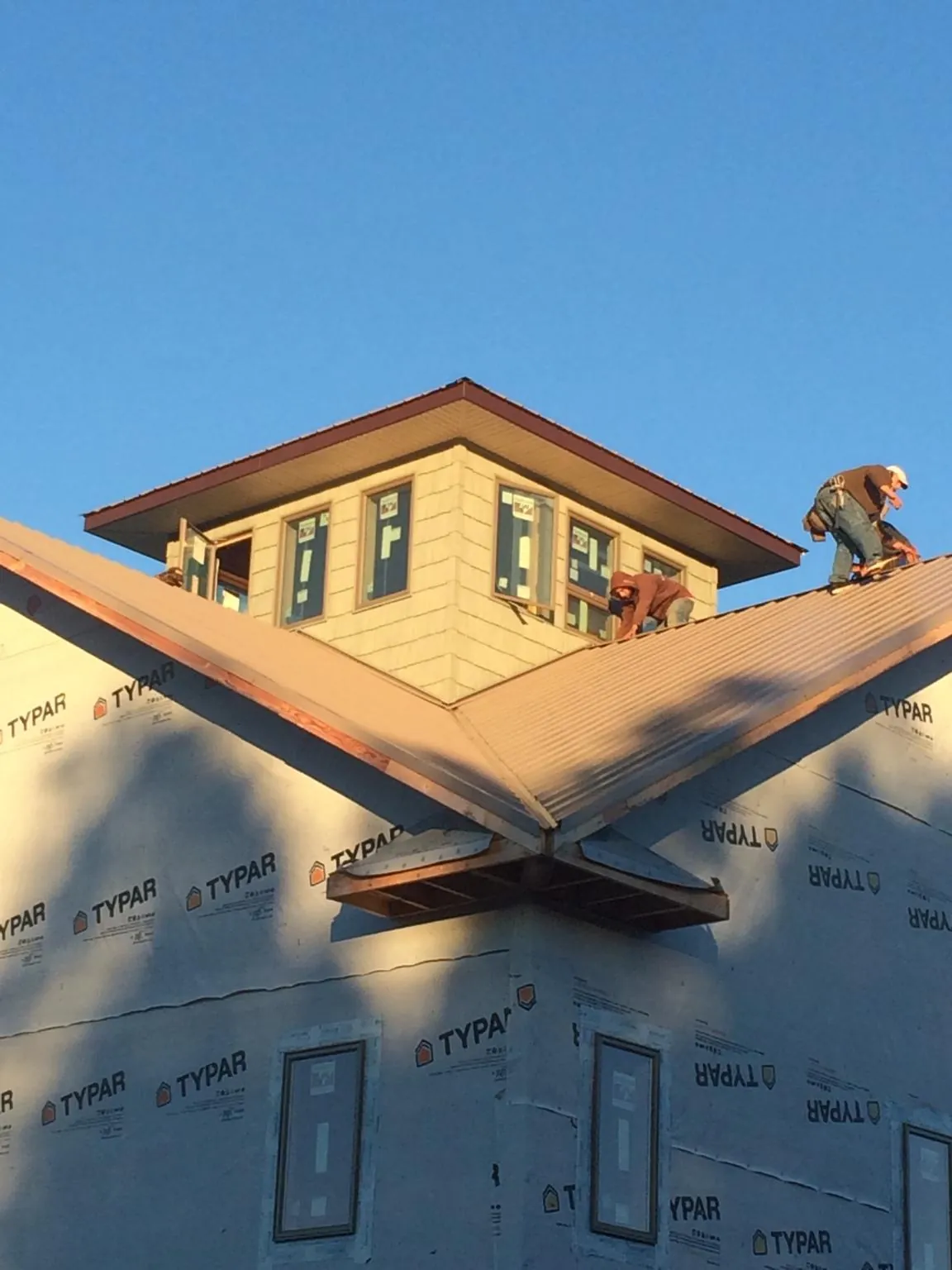 Roofers working around a rooftop cupola on a new metal roof at sunset — Roof Waterproofing in Waldron by Roofing Brothers